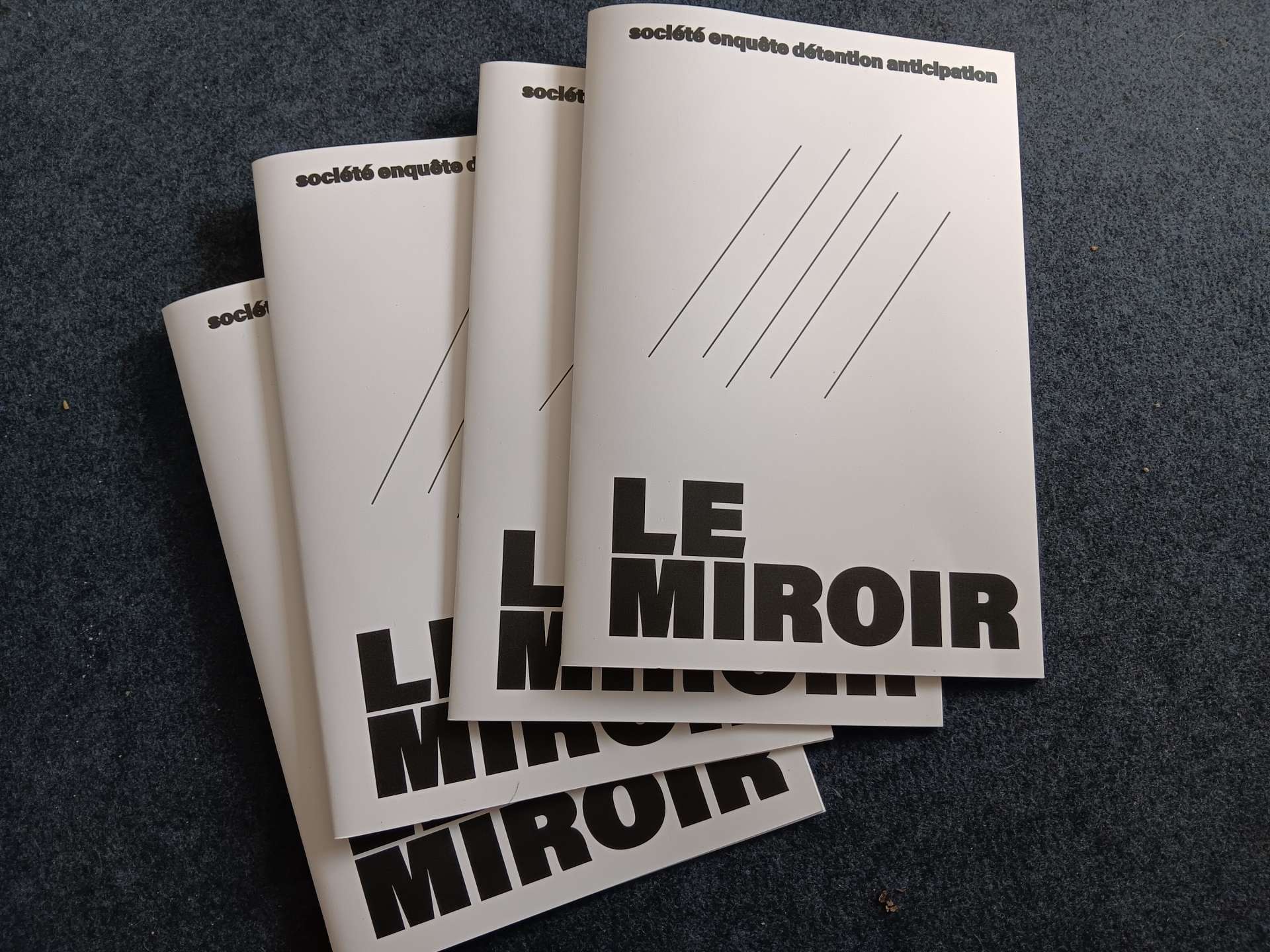 Photographie en noir et blanc de quatre livrets identiques, intitulés "Le miroir"
